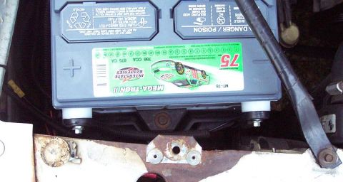 1985 Ford Crown Victoria LTD - A close-up of a car battery, a sticker with a race car graphic and the number 75.