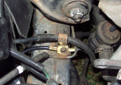 1985 Ford Crown Victoria LTD - Detail of a vehicle's brake line junction, with visible hoses and mounting hardware.