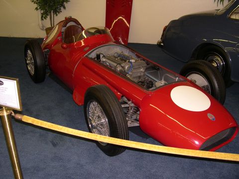 2002 Ford Focus - A vintage red race car is displayed indoors next to another vehicle.