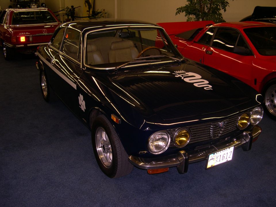Dark blue coupe with white stripe and clover emblem, front quarter view, chrome bumper, yellow headlights