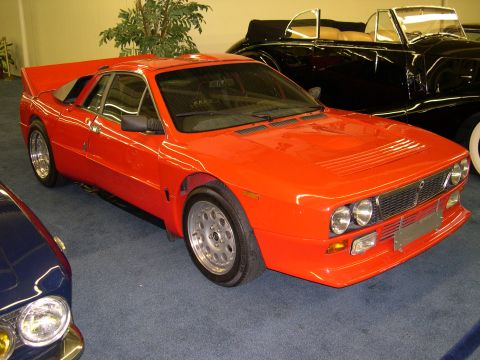 2002 Ford Focus - Orange Lancia Stratos sports car parked indoors next to a black convertible.