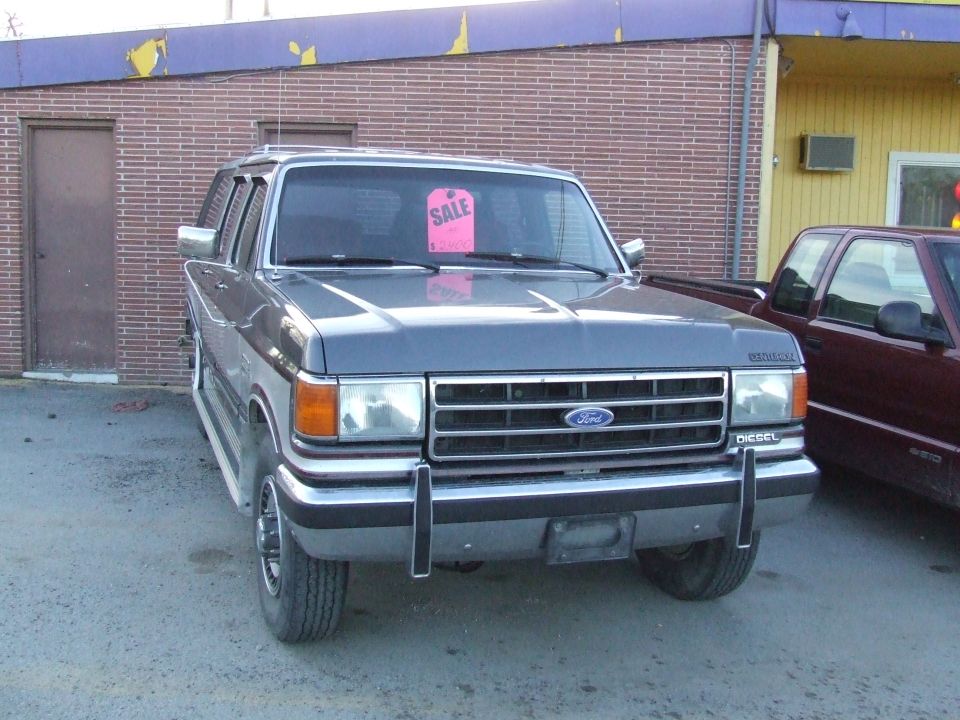 1991 Ford C-350 Centurion Conversions van, gray, parked, with a pink "SALE" tag on windshield