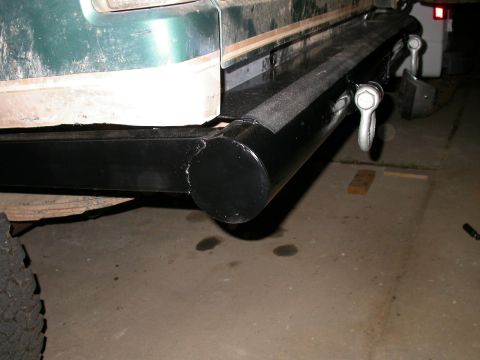 1990 Ford Bronco - Night shot of a black shop-built tube rear bumper on a green SUV, showing the rounded welded end cap at the corner and two chrome D-ring sh…