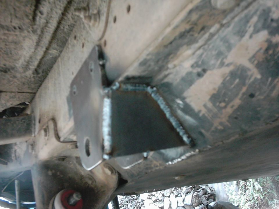 Custom welded bracket attached to a vehicle's frame, likely for suspension modification