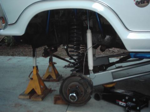 1978 Ford Bronco - Undercarriage view of a white vehicle, lifted on jack stands, with visible suspension components like coil springs and shocks.