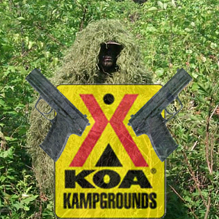 1969 Ford Mustang - A KOA Kampgrounds sign is displayed with crossed pistols and a person in a ghillie suit in the background.