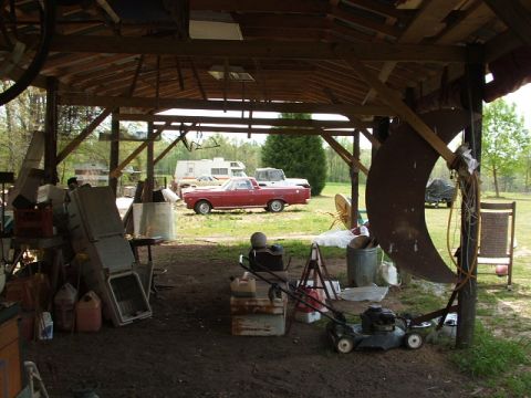 1966 Ford Ranchero - A red pickup truck is parked inside a rustic open-air shed.