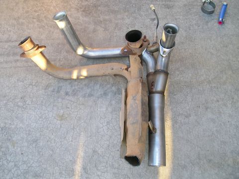 1993 Ford Bronco - Exhaust system components, including a catalytic converter and pipes, laid out on a concrete surface.