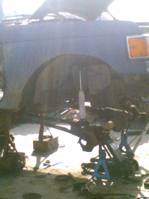 1989 Ford Bronco - Front suspension of a 1989 Ford Bronco is elevated on jack stands for maintenance.