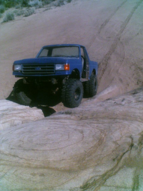 1989 Ford Bronco - This modified truck is navigating a challenging off-road course with steep inclines and rocky surfaces.