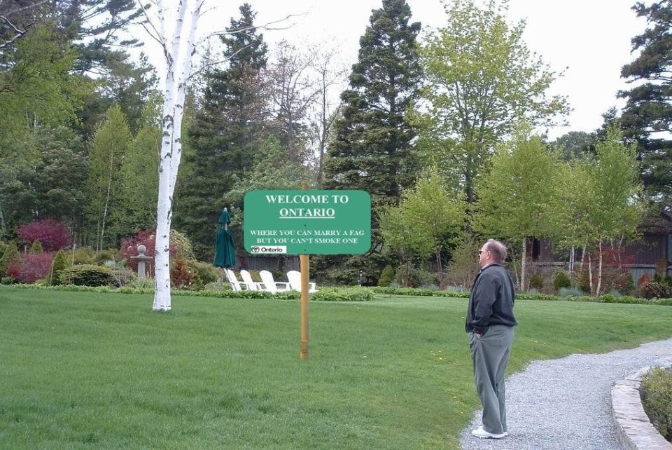 Man looking at a 'Welcome to Ontario' sign with a controversial message
