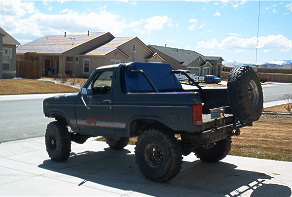 Dark blue Ford Bronco, lifted, with large tires and a spare tire on the rear bumper