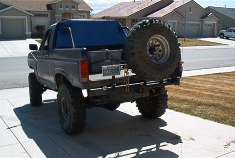 1986 Ford Bronco - This 1986 Ford Bronco features a blue soft top and a large spare tire mounted on the rear bumper.