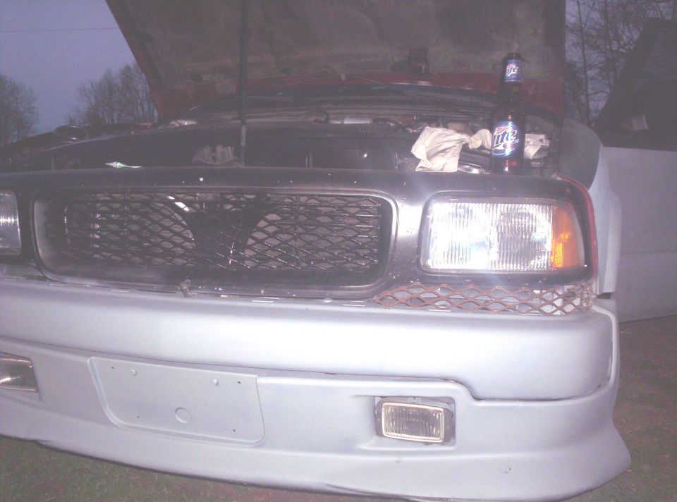 Front of a 1998 Chevrolet S10 pickup truck with hood open, showing grille and headlights