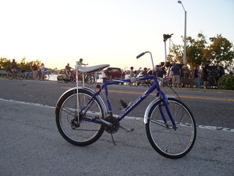 1994 Ford Probe - A blue Schwinn bicycle is parked on the side of the road with other cyclists in the background.