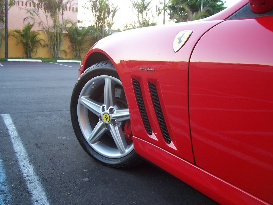 Red Ferrari side view with distinctive wheel and fender vents