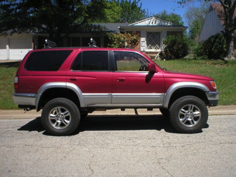 1996 Toyota 4Runner - Side profile of a red 1996 Toyota 4Runner SUV with silver trim and roof racks.