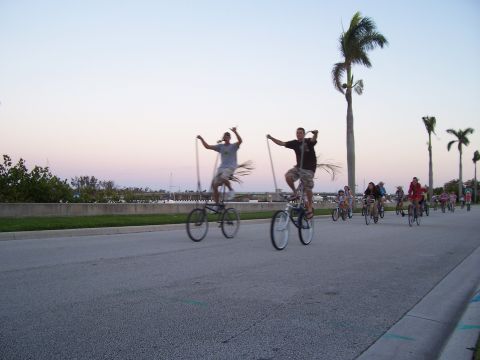 1994 Ford Probe - A group of people ride tall bicycles along a coastal road at sunset.