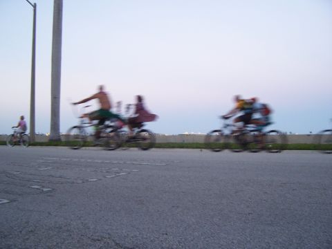 1994 Ford Probe - A group of cyclists ride along a road at dusk, with a utility pole visible on the left.