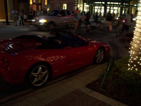 1994 Ford Probe - A red convertible sports car is parked on the side of the street at night, with other vehicles and pedestrians in the background.