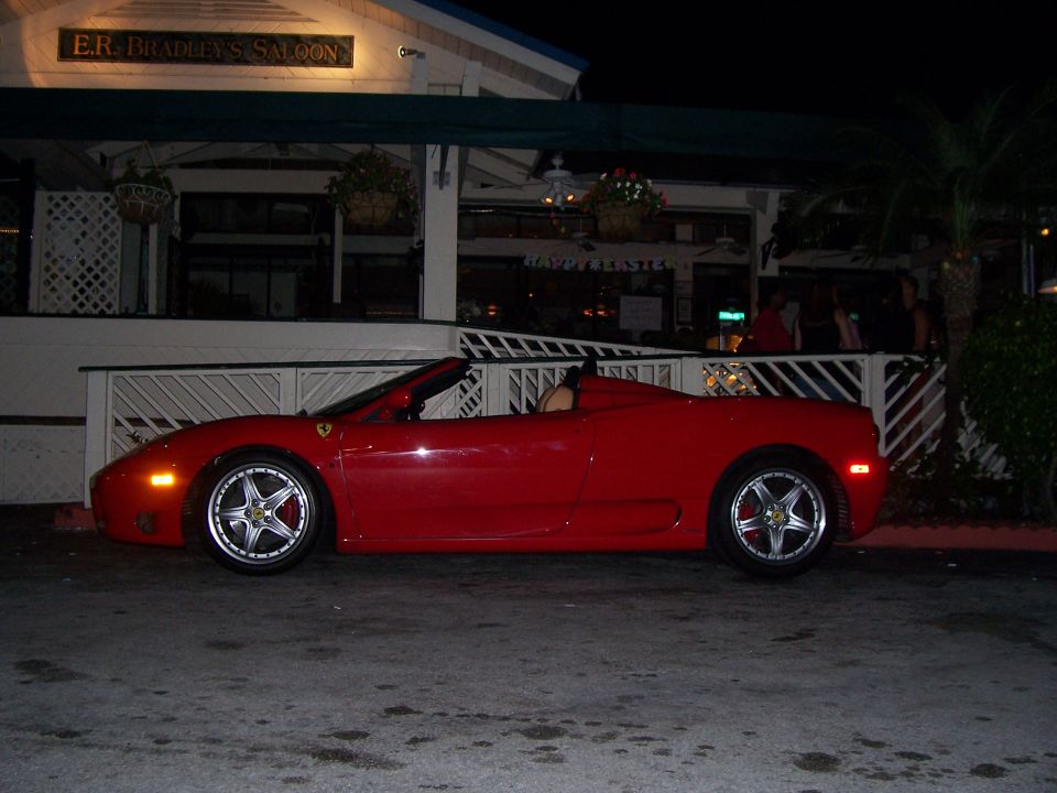 Red convertible sports car parked in front of a building at night