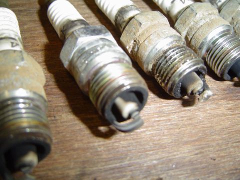 1989 Ford Bronco - A close-up shot shows several used spark plugs with varying degrees of wear and carbon fouling.