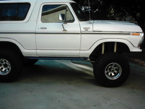 1978 Ford Bronco - Side profile of a lifted white Ford Bronco XLT with the Bronco fender badge visible, chrome bodyside molding, a white removable hardtop, an…