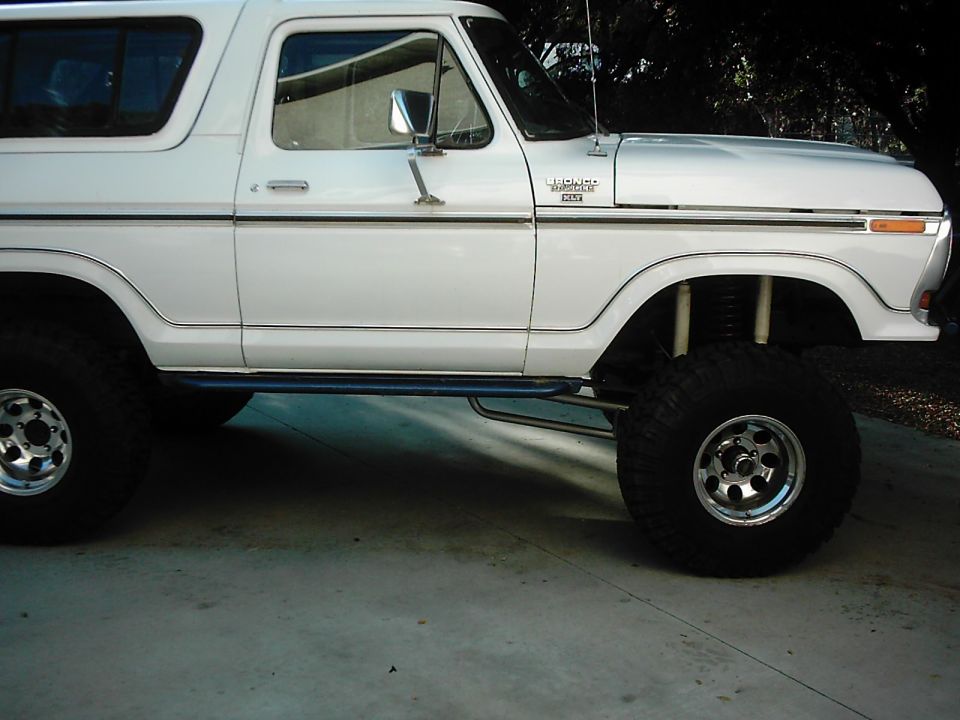 Lifted white Ford Bronco XLT side view on polished wheels and mud tires