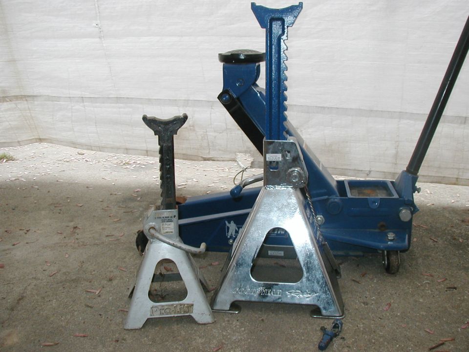 Two jack stands (Pro-Lift and Goodyear) in front of a blue floor jack on concrete