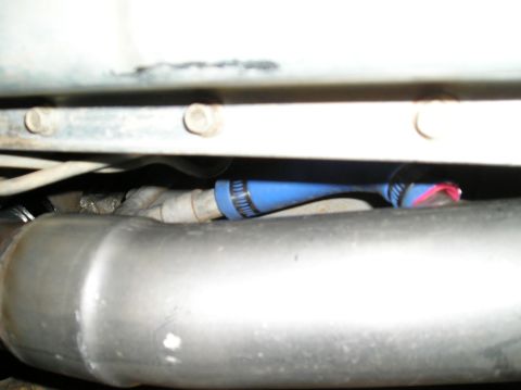 1993 Ford Bronco - Close-up of vehicle undercarriage components, including an exhaust pipe and a blue hose.