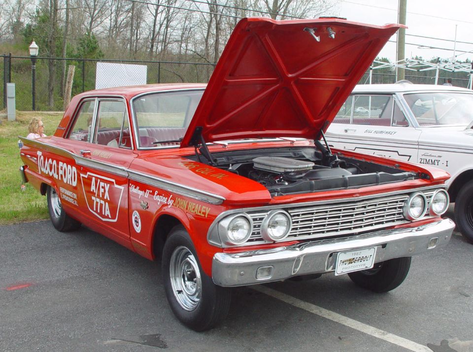 Red Tasca Ford A/FX Fairlane drag car with hood up showing its V8 at a car show