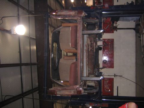 1978 Ford Bronco - The underside of a vehicle is visible as it's held upside down on a lift in a workshop.