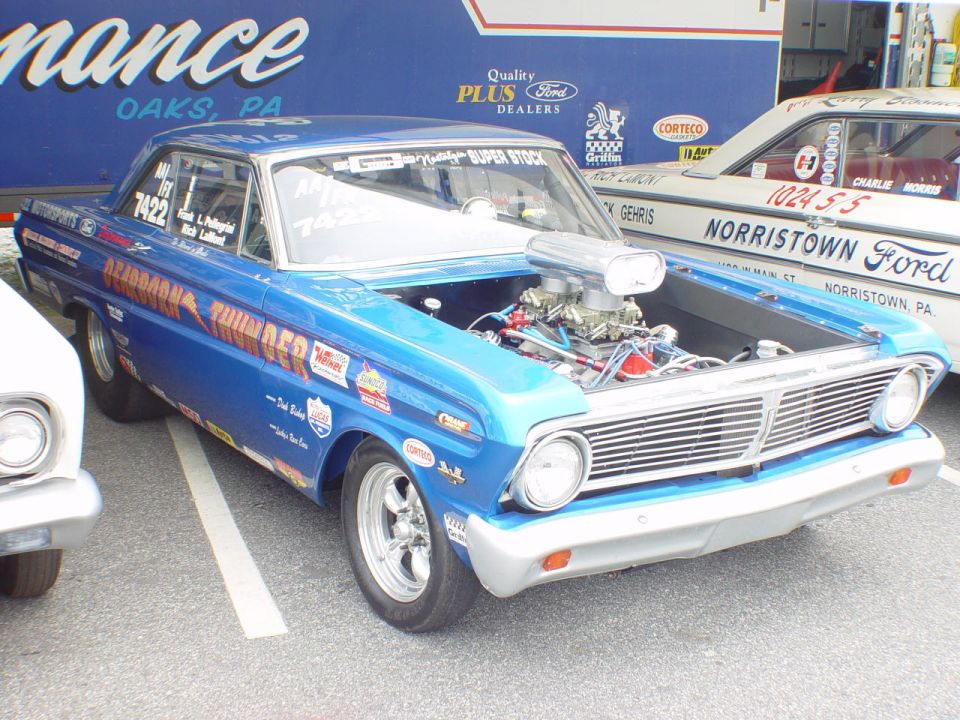 Blue Dearborn Thunder Ford drag car with exposed tunnel-ram engine at a race paddock