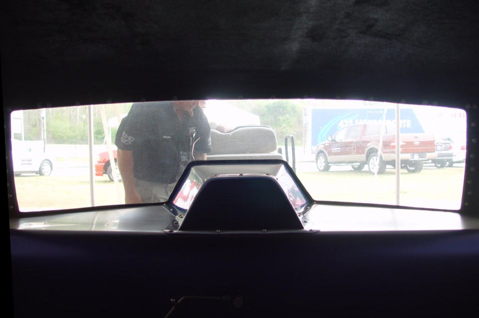 Interior view out a wide window toward a paddock with a maroon SUV and trailer