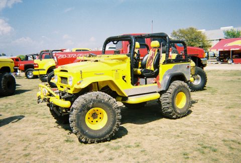 1989 Ford F-350 - A bright yellow off-road vehicle is parked outdoors with other vehicles in the background under a clear sky.