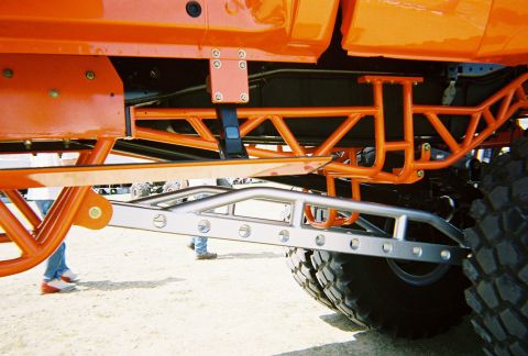 1989 Ford F-350 - Close-up view of the custom suspension and frame of an orange off-road truck.