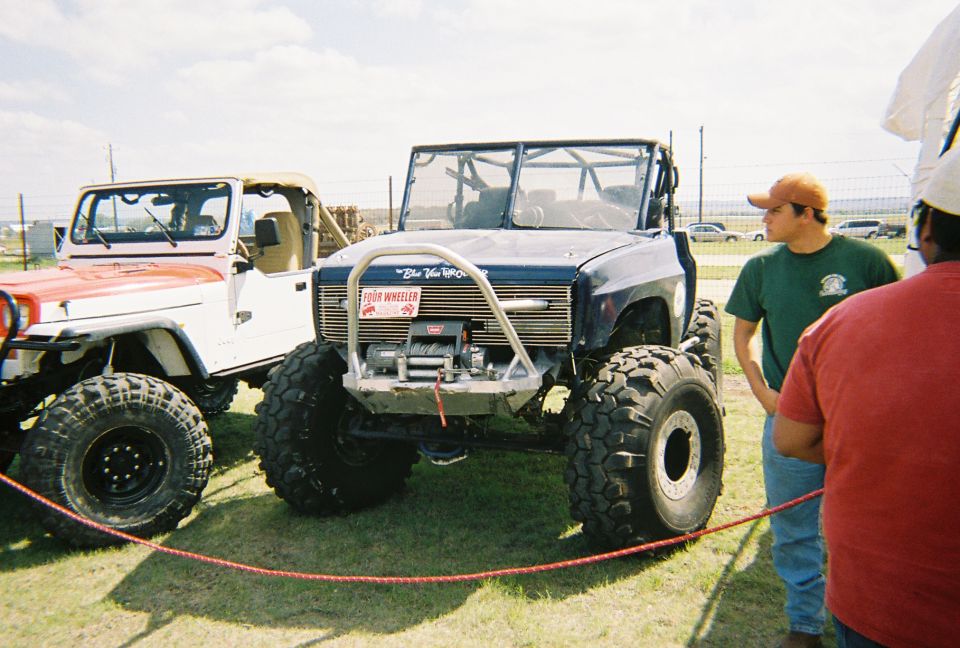 Big blue off-road truck with winch and a white Jeep next to it