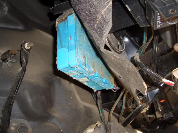Close-up of a blue electronic control module and wiring harness inside a vehicle