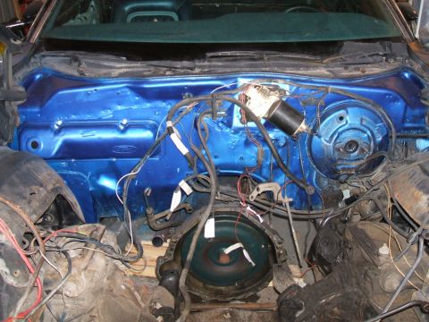 1974 Ford Ranchero - The engine bay of a vehicle shows a bright blue painted firewall with wiring and transmission components visible.