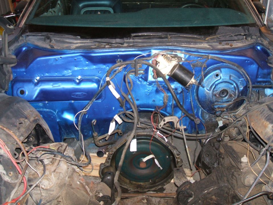 Empty engine bay with blue Ford firewall, wiper motor and wiring during restoration