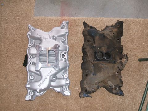 1974 Ford Ranchero - Two V8 intake manifolds shown side by side on carpet: a new bright silver Edelbrock Performer aluminum intake with square-bore carburetor p…