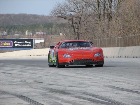 2000 Ford Crown Victoria - A red stock car with the number 80 is on a race track, with a billboard in the background.