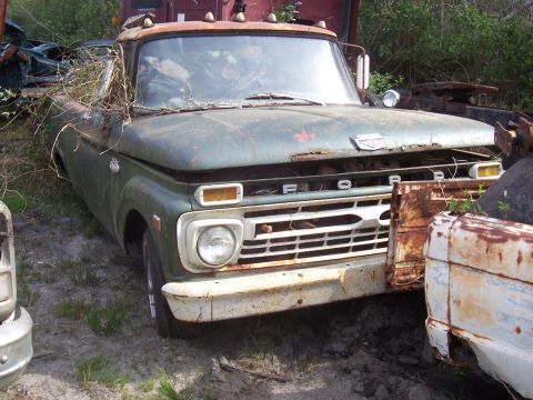 1978 Ford Bronco - This weathered Ford truck sits in a junkyard, showing signs of significant rust and neglect.