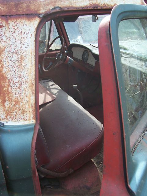 1978 Ford Bronco - The interior of a weathered truck shows a worn red seat and a partial view of the dashboard.