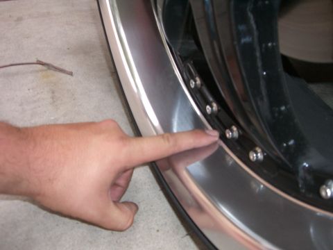 1996 Ford Probe - A finger points to the bolts on a shiny metal wheel rim.