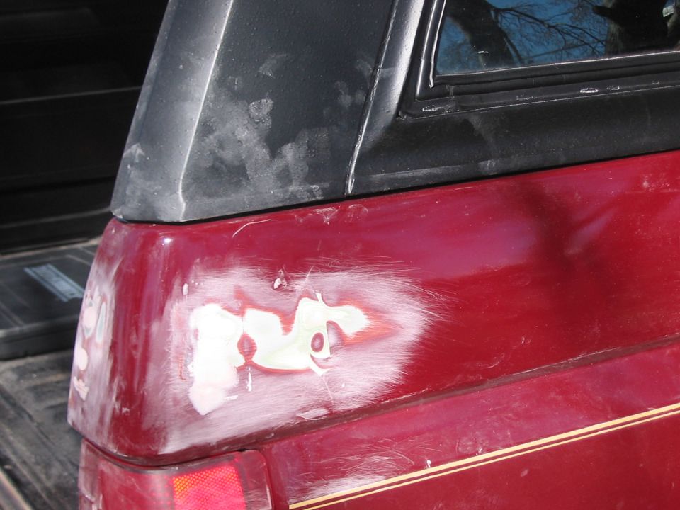 Red SUV rear quarter panel with body filler and primer