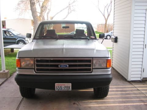 1991 Ford Bronco - A silver Ford F-Series truck is parked in a driveway next to a white shed.