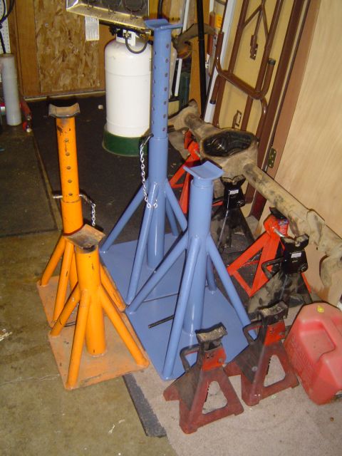 1989 Ford Bronco - A collection of automotive jack stands and a differential are stored in a garage.