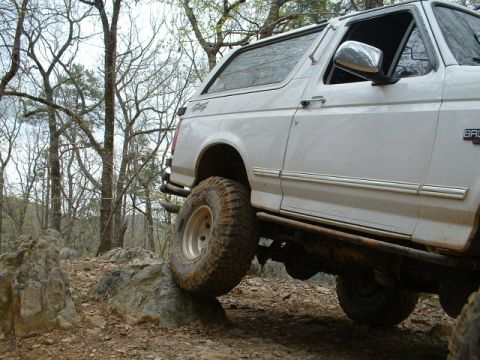1987 Ford F-150 - Ford Bronco navigates rocky terrain on an off-road trail.