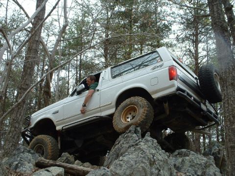 1987 Ford F-150 - A white Ford Bronco navigates a rocky trail, its off-road capabilities.